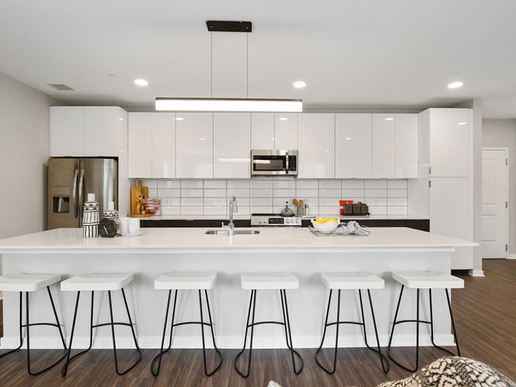 Huge apartment kitchen with white cabinetry, breakfast bar, and stainless steel appliances